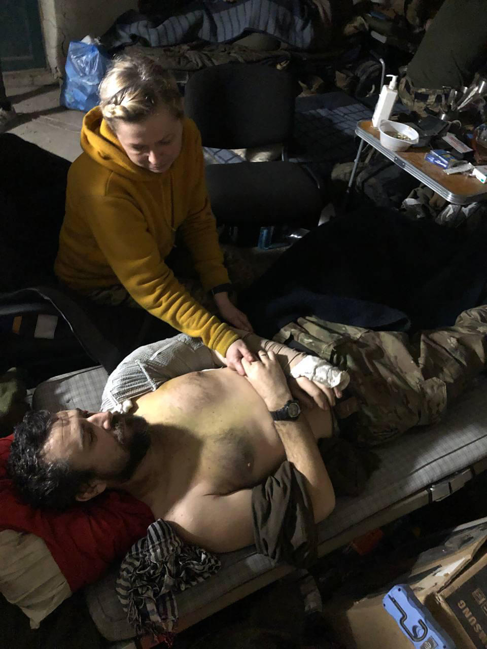 This recent but undated photo provided Friday, April 29, 2022 by the wife of a member of the Azov Regiment shows a woman comforting a wounded man inside the Azovstal steel plant, in Mariupol, eastern Ukraine. (Anonymous via AP )