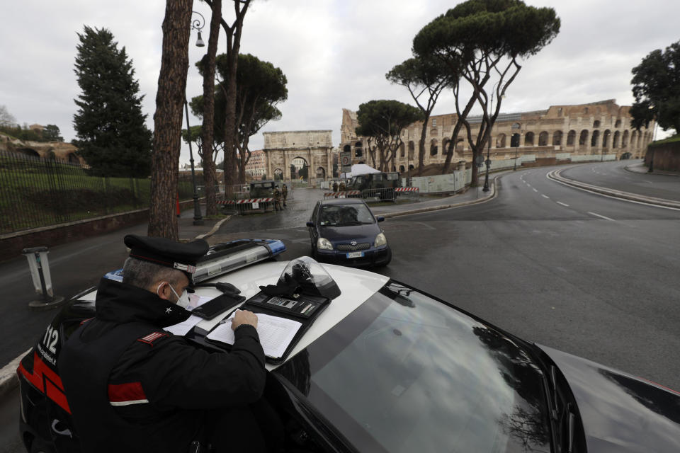 Italian Carabinieri officers check vehicles near the Colosseum in Rome, Thursday, Dec. 24, 2020. Italians are easing into a holiday season full of restrictions, and already are barred from traveling to other regions except for valid reasons like work or health. Starting Christmas eve, travel beyond city or town borders also will be blocked, with some allowance for very limited personal visits in the same region. (AP Photo/Gregorio Borgia)