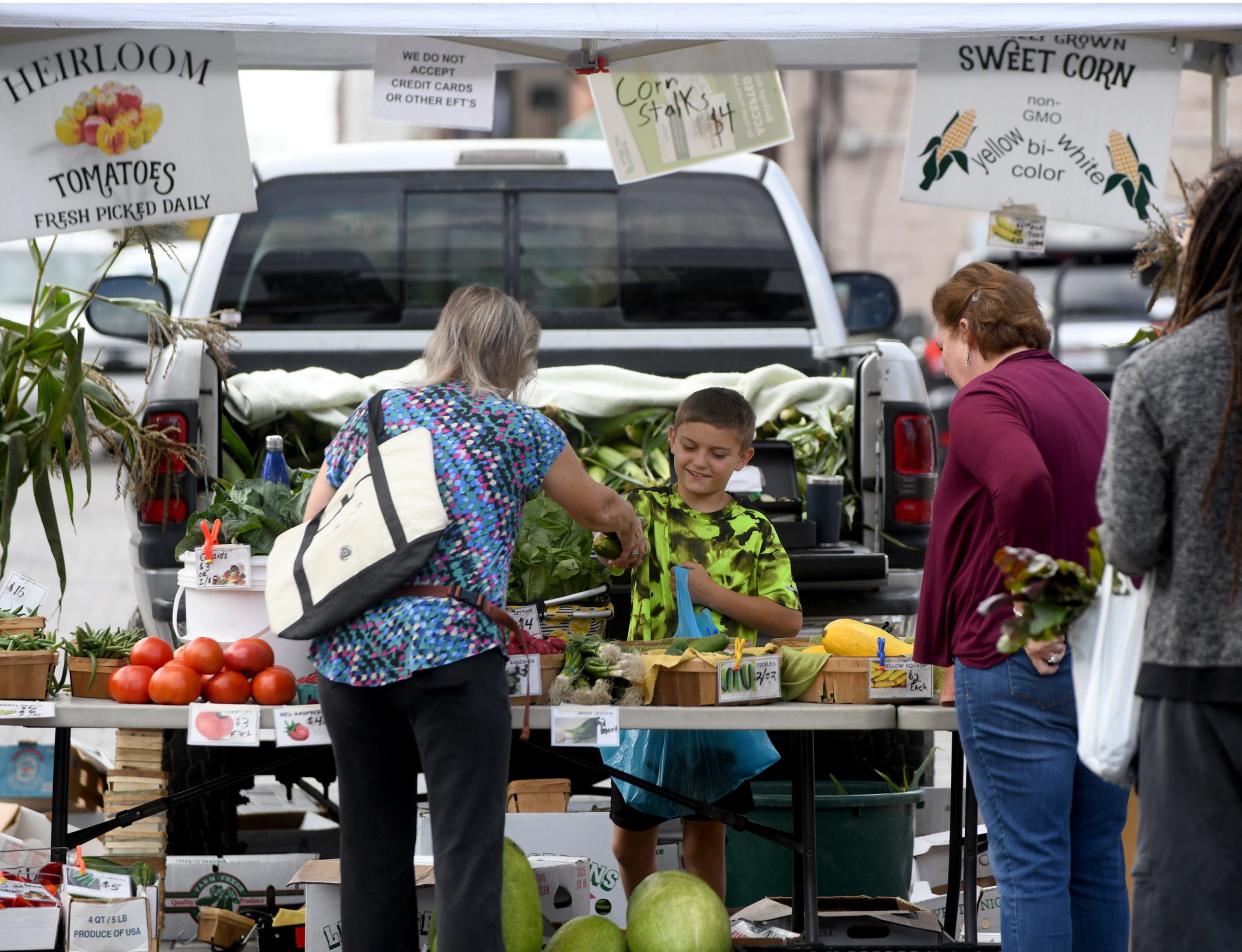 Joe May, 10, helps father Mike May sell a variety of produce from May's Produce of Randolph at the Canton Farmers Market in downtown Canton.