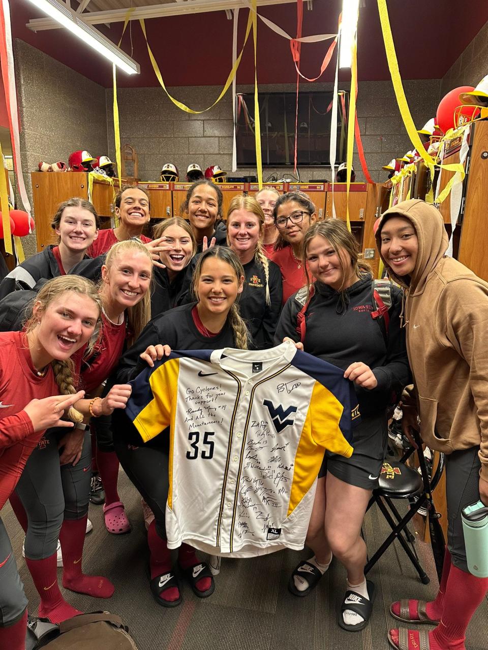 The Iowa State softball team poses with the jersey signed by the West Virginia baseball team.