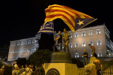 Protesters wave a "Estelada" (Catalonian separatist flag) (R) and a Greek flag in front of the parliament building during an anti-austerity rally in Athens, Greece, June 29, 2015. REUTERS/Marko Djurica