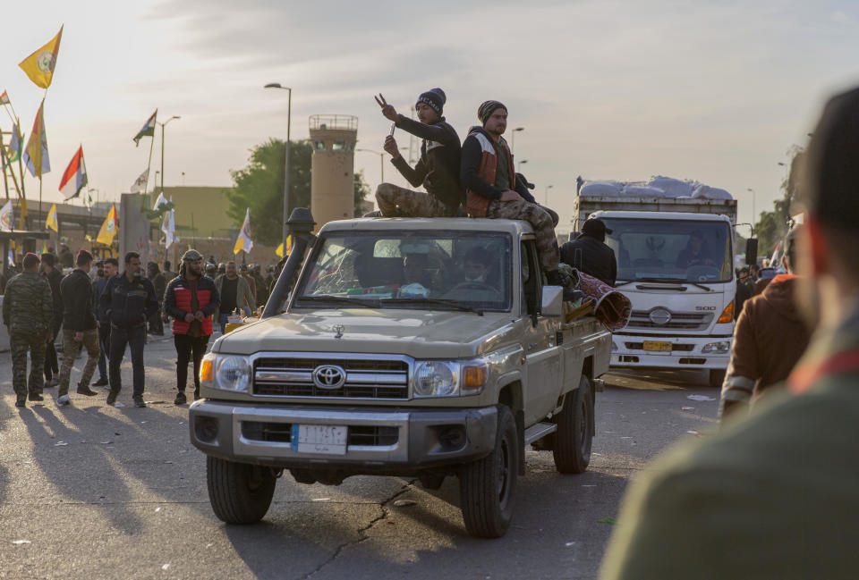 Pro-Iranian militiamen and their supporters board trucks loaded with items from a sit-in while driving away from the U.S. Embassy, in Baghdad, Iraq, Wednesday, Jan. 1, 2020. U.S. troops fired tear gas on Wednesday to disperse pro-Iran protesters who were gathered outside the U.S. Embassy compound in Baghdad for a second day. (AP Photo/Nasser Nasser)