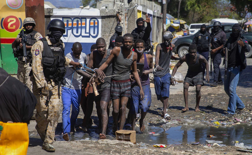 Recaptured inmates are led by police outside the Croix-des-Bouquets Civil Prison after an attempted breakout, in Port-au-Prince, Haiti, Thursday, Feb. 25, 2021. At least seven people were killed on Thursday after several inmates tried to escape from the prison, eyewitnesses told The Associated Press. (AP Photo/Dieu Nalio Chery).