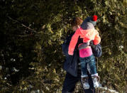 Royal Canadian Mounted Police (RCMP) officers assist a child from a family that claimed to be from Sudan as they walk across the U.S.-Canada border into Hemmingford, from into Hemmingford, Canada, from Champlain in New York, U.S., February 17, 2017. REUTERS/Christinne Muschi