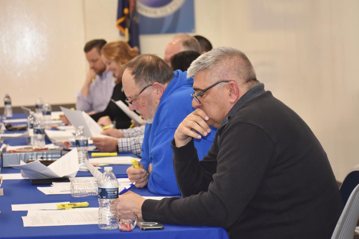 Adrian Public Schools Board of Education members, including trustees Jay Marks and Michael Ballard, foreground, review information during a workshop March 28, 2022, to develop the board's relationship with new Superintendent Nate Parker.