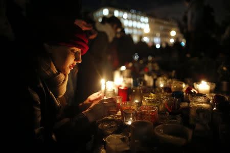 FILE PHOTO: A woman lights a candle as people gather on the Place de la Republique square to pay tribute to the victims of last year's shooting at the French satirical newspaper Charlie Hebdo, in Paris, France, January 7, 2016. REUTERS/Stephane Mahe