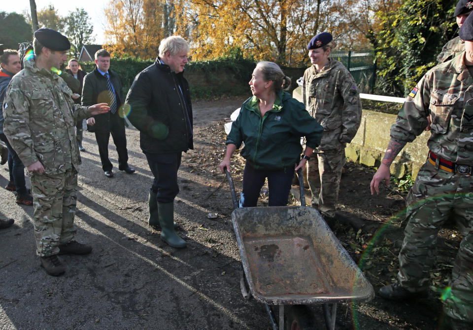 Prime Minister Boris Johnson talks with a local woman pushing a wheelbarrow during a visit to Stainforth, Doncaster, to see the recent flooding.