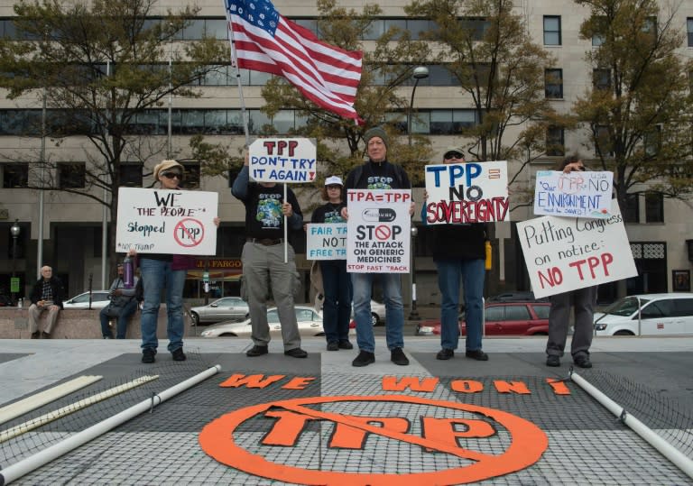 People hold signs as they demonstrate against the Trans-Pacific Partnership (TPP) trade agreement in Washington, DC, on November 14, 2016