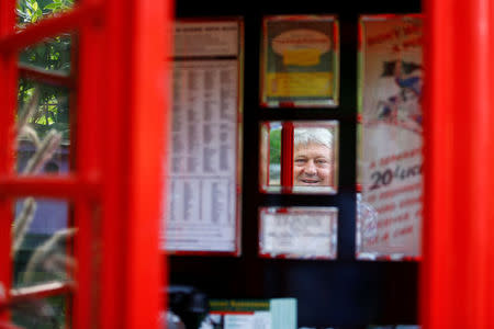 Gary Blackburn, a 53-year-old tree surgeon from Lincolnshire, Britain, is seen in the mirror of his original British telephone box previously located at Trafalgar Square in London at his British curiosities collection called "Little Britain" in Linz-Kretzhaus, south of Germany's former capital Bonn, Germany, August 24, 2017. REUTERS/Wolfgang Rattay