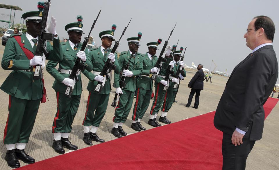 French President Francois Hollande reviews troops as he arrives at the Abuja airport, Nigeria, Thursday, Feb. 27, 2014. Hollande attends the International conference on Peace and Security in Abuja. Hollande is in Nigeria for a one-day official visit. (AP Photo/Philippe Wojazer, Pool)