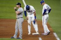 New York Yankees first baseman Luke Voit, left, stands by as Texas Rangers first base coach Corey Ragsdale (43) checks on Joey Gallo, center, in the third inning of a baseball game in Arlington, Texas, Monday, May 17, 2021. Gallo, who earned a walk in the at-bat, stumbled on the bag looking back at the plate landing awkwardly on the ground. Gallo continued playing in the game. (AP Photo/Tony Gutierrez)