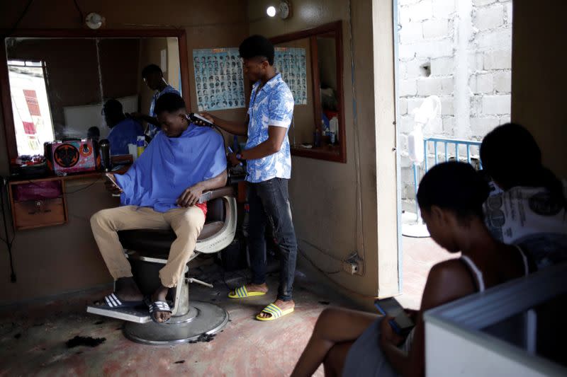 A man gets his hair cut at a barber shop which runs on solar panels in Port-au-Prince
