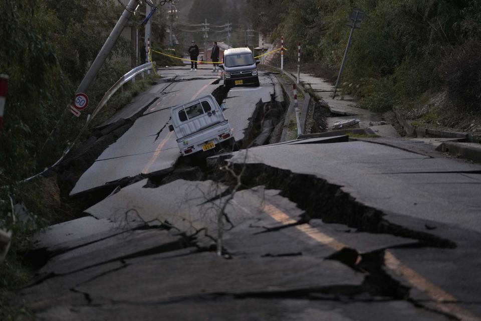 Bystanders look at damage near Noto town in the Noto peninsula facing the Sea of Japan, northwest of Tokyo, Tuesday, Jan. 2, 2024, following Monday's deadly earthquake. (AP Photo/Hiro Komae)