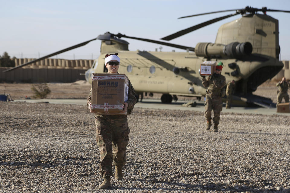 In this Tuesday, Dec. 24, 2019, photo, U.S. service members deliver Christmas gifts to their comrades on a base near the al-Omar oilfield in eastern Syria. It's an operation is called Holiday Express - in addition to delivering presents, the U.S.-led coalition forces brought a U.S. military band to play Christmas carols and music to several bases in eastern Syria. (AP Photo/Farid Abdul-Wahid)