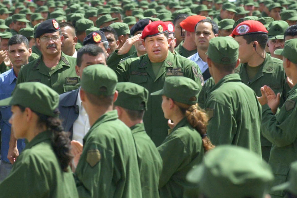 FILE - In this April 13, 2005 file photo, Venezuelan Defense Minister Jorge Garcia Carneiro, back left in black beret, accompanies Venezuelan President Hugo Chavez, center, in a ceremony activating the military reserve in Ft. Tiuna in Caracas, Venezuela. Garcia Carniero, a Venezuelan state governor who once served as defense minister for former President Hugo Chavez has died, officials said Saturday, May 22, 2021. He was 69. (AP Photo/Leslie Mazoch, File)