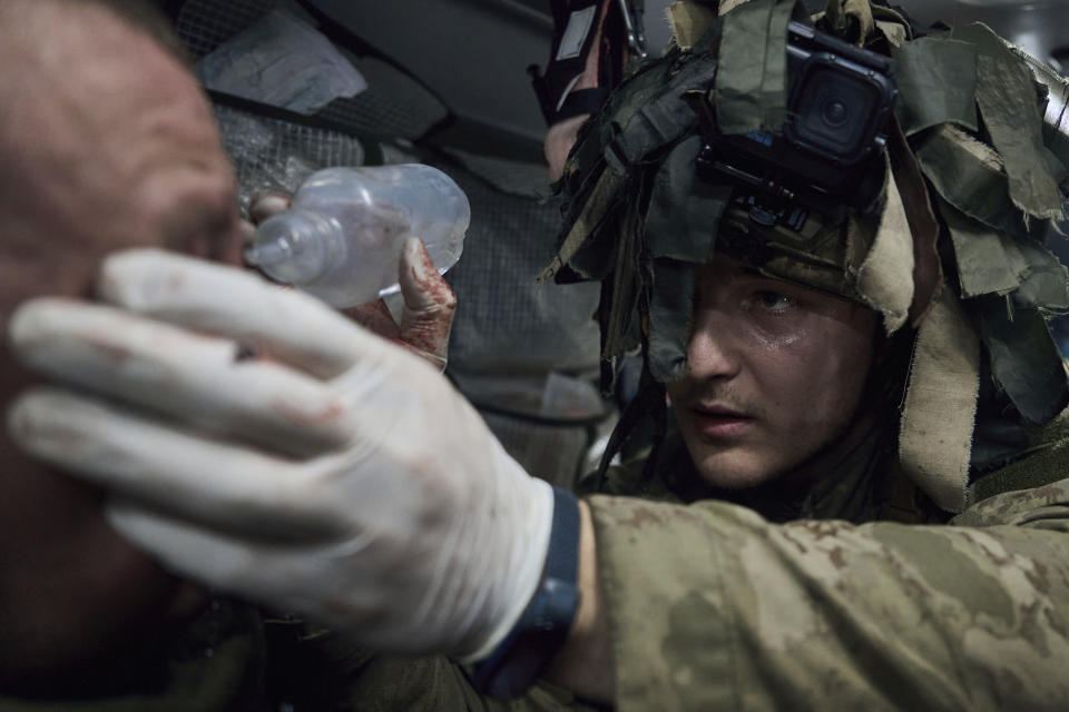 A military medic gives first aid to a soldier wounded in a battle near Kremenna in the Luhansk region, Ukraine, Monday, Jan. 16, 2023. (AP Photo/LIBKOS)