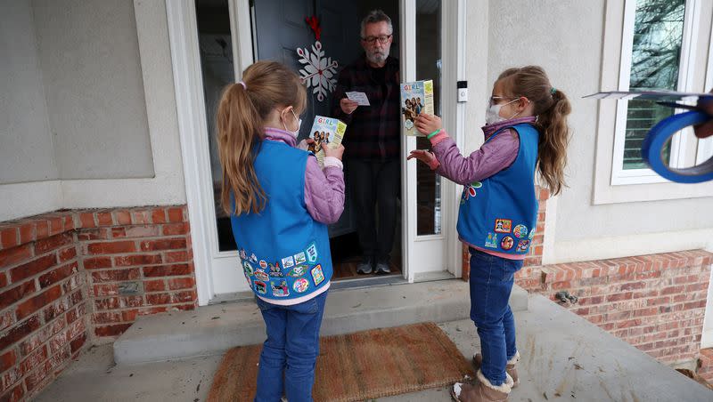 Robert Ross talks with Annie and Juliet Agy as they go door to door selling Girl Scout Cookies in Cottonwood Heights on Jan. 25, 2022.
