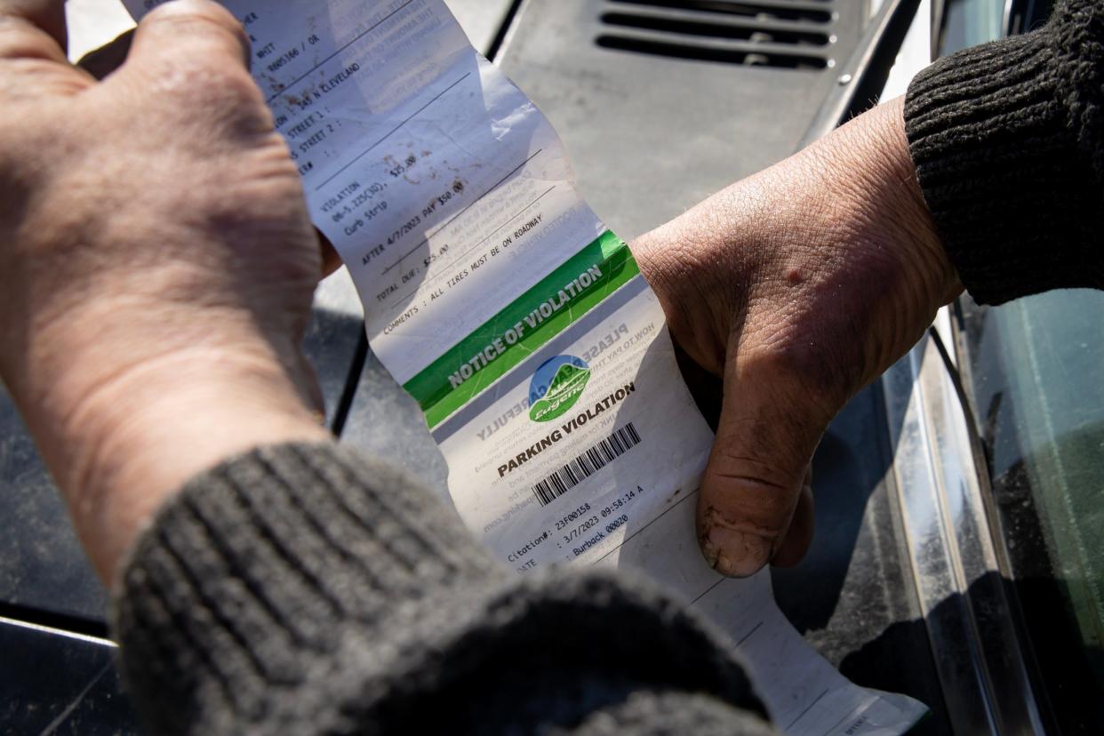 A Eugene motorist looks over a parking violation he received in Eugene when his trailer was impounded in March of 2023.