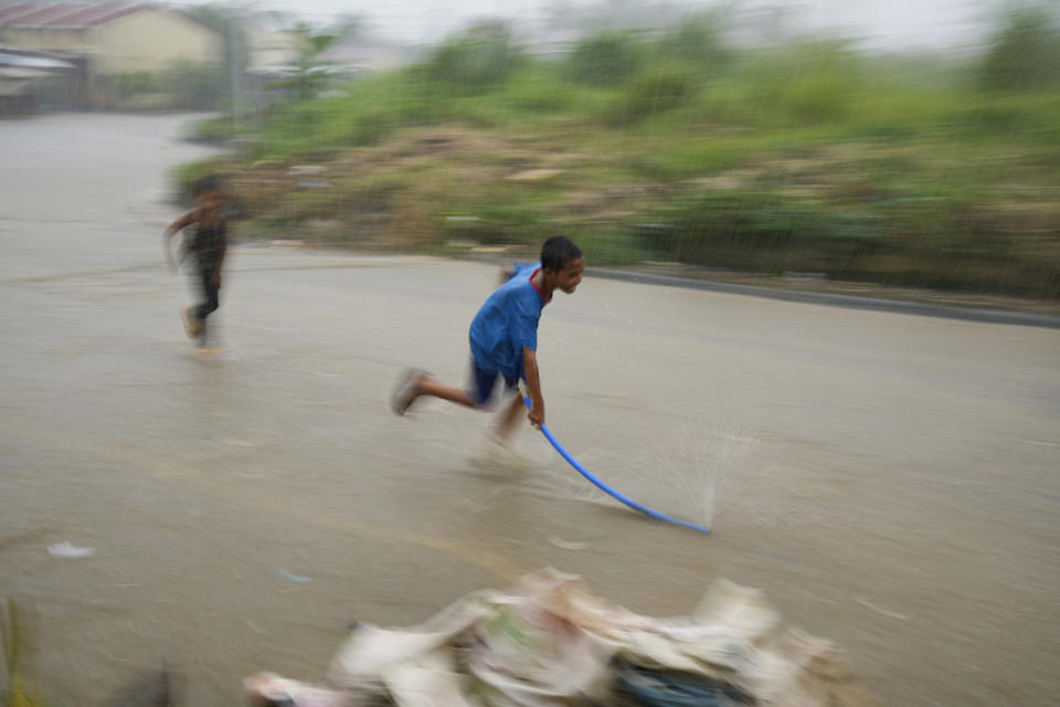 Kids play during rain at a relocation site for victims of super Typhoon Haiyan in Tacloban, central Philippines on Monday, Oct. 24, 2022. About 40% of the population of Tacloban was relocated to safer areas after super Typhoon Haiyan wiped out most of the villages, killing thousands when it hit central Philippines in 2013. (AP Photo/Aaron Favila)