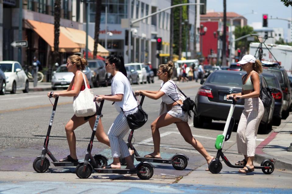 Young women ride shared electric scooters in Santa Monica, California, on July 13, 2018. - Cities across the U.S. are grappling with the growing trend of electric scooters which users can unlock with a smartphone app. Scooter startups including Bird and Lime allow riders to park them anywhere that doesn't block pedestrian walkways but residents in some cities, including Los Angeles, say they often litter sidewalks and can pose a danger to pedestrians. (Photo by Robyn Beck / AFP) (Photo by ROBYN BECK/AFP via Getty Images)