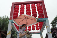 Residents walk with an umbrella during a rainy day in Beijing, Sunday, Aug. 14, 2022. (AP Photo/Ng Han Guan)