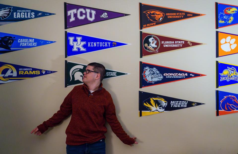 Owen Carr admires his collection of sports pennants Wednesday, Dec. 6, 2023, inside his room in Avon, Indiana. At an early age, Carr fell in love with the color of teams, as well as their mascots. "It was a March Madness one year where they had the all the brackets and the mascots, you know, the college names and logos on the screen," Kevin Carr, Owen's father, said. "He started to tune into that."