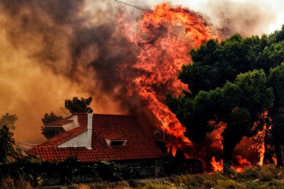 A house is threatened by a huge blaze during a wildfire in Kineta, near Athens, on Monday (Picture: Getty)