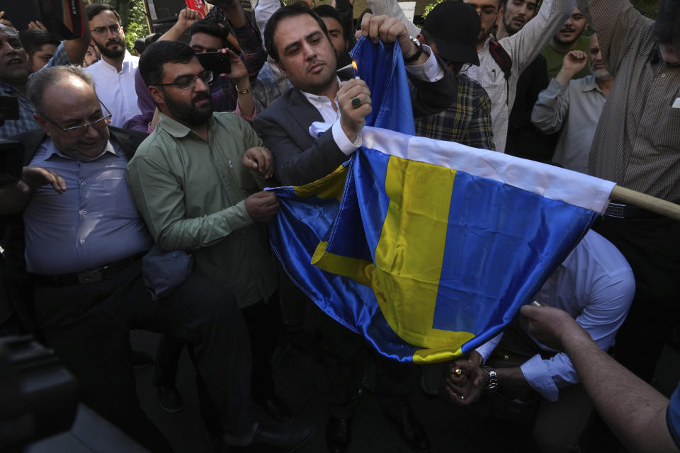 Iranian demonstrators burn a Swedish flag during a protest of the burning of a Quran in Sweden, in front of the Swedish Embassy in Tehran, Iran, Friday, June 30, 2023. On Wednesday, a man who identified himself in Swedish media as a refugee from Iraq burned a Quran outside a mosque in central Stockholm. (AP Photo/Vahid Salemi)