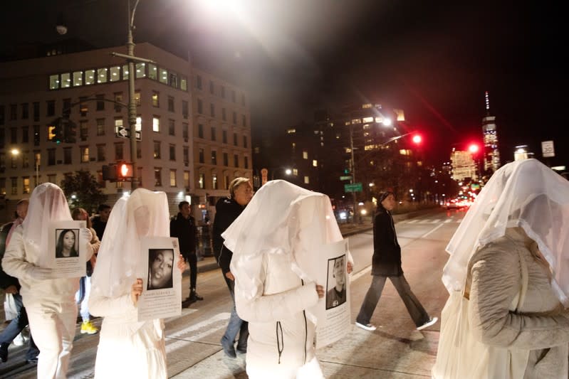 Activists dress in white and hold images of slain members of the LGBTQ community during a demonstration to commemorate Transgender Day of Remembrance in New York City