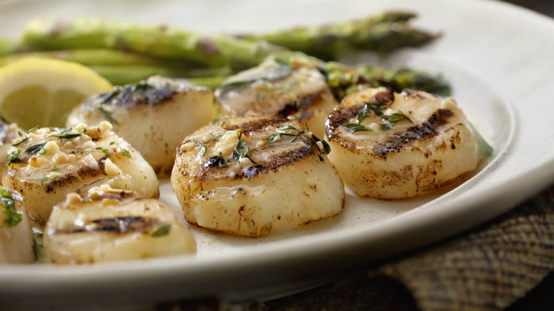 Grilled scallops on plate with lemon and asparagus