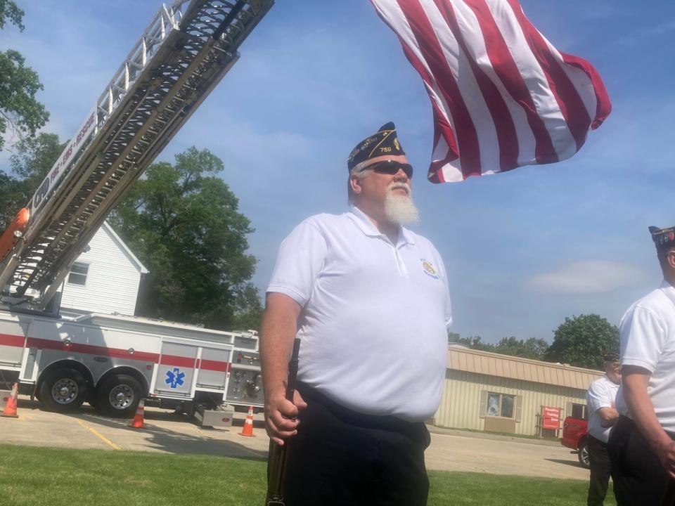 Greg Harris of American Legion Post 759 stands at attention as a flag from the Chatham Fire Department blows in the background at the start of a Memorial Day service at Veterans Memorial Park in Chatham. Harris was part of a guard that fired a 21-gun salute at the service.