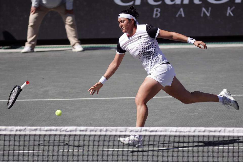 Ons Jabeur, of Tunisia, throws her racket as she misses the ball against Belinda Bencic of Switzerland, during the finals at the Charleston Open tennis tournament in Charleston, S.C., Sunday, April 10, 2022. (AP Photo/Mic Smith)