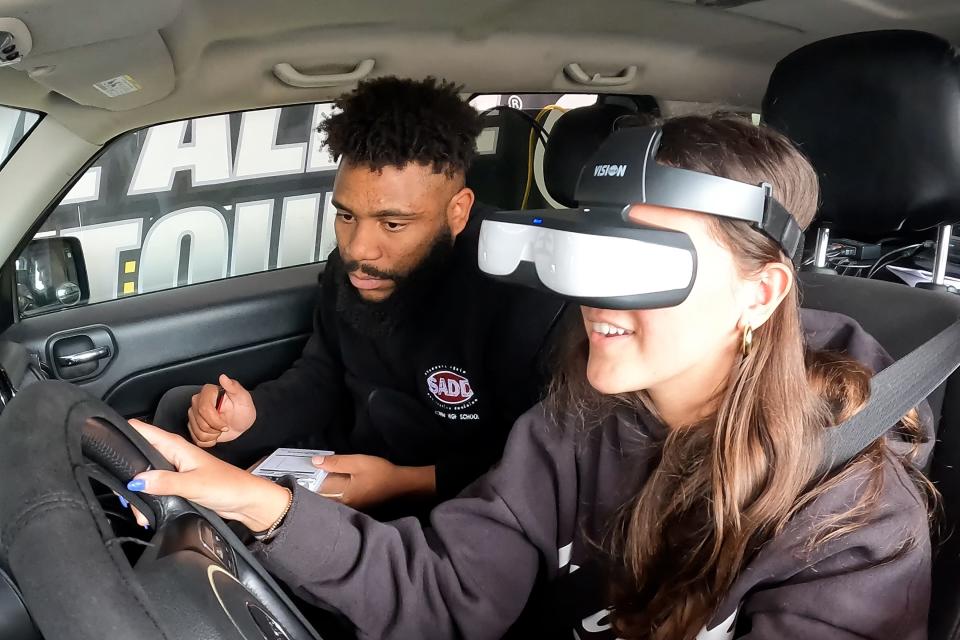 Lily DiPalma, 18, of Matawan participates in an Arrive Alive Tour drunk driving, distracted driving and marijuana-driving simulator experience as Shaquille Hill, an Arrive Alive Tour traveling educator, records her performance during Road Safety Day at Matawan Regional High School in Aberdeen Twp., NJ Thursday, April 11, 2024.