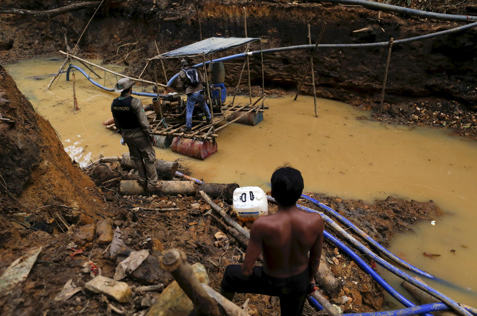 A Yanomami man, right, stands near an illegal gold mine on Indigenous land in the heart of the Amazon rainforest, in Roraima state, Brazil, in April 2016. Illegal miners continue to plague the area, sawing down trees and poisoning rivers with mercury in their lust for gold.<span class="copyright">Bruno Kelly—Reuters</span>