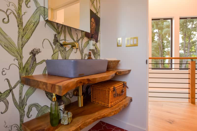 Sink atop live edge shelving in bathroom with corn wallpaper.