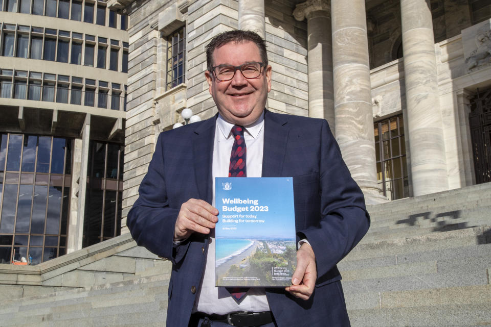 New Zealand Finance Minister Grant Robertson poses with the front cover of his Budget 2023 on the steps of Parliament in Wellington, New Zealand, Wednesday, May 17, 2023. New Zealand’s government on Thursday offered some modest financial relief to many people by making most prescription medicines free and increasing subsidies for childcare and public transportation. (Mark Mitchell/New Zealand Herald via AP)