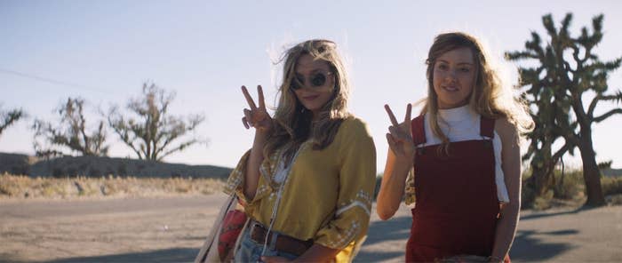 Elizabeth Olsen and Aubrey Plaza giving the peace sign as they stand outside in a scene from "Ingrid Goes West"