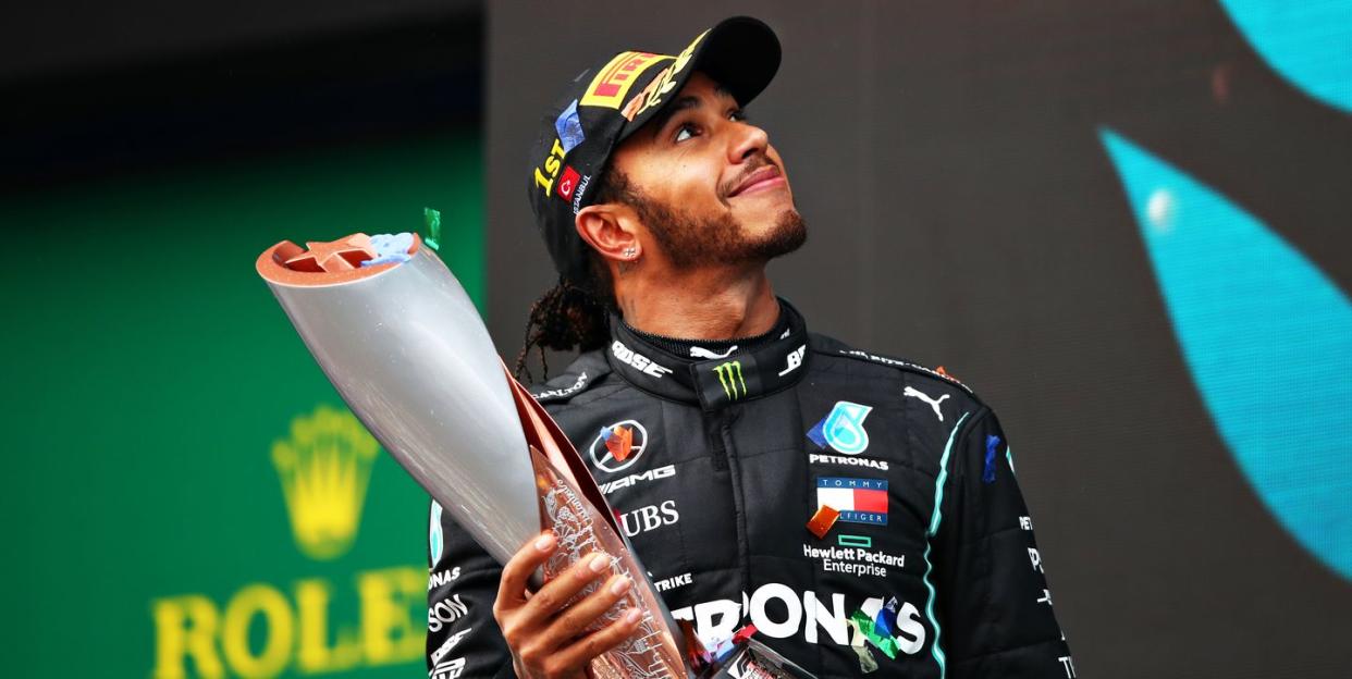 sir lewis hamilton smiles as he holds a trophy at the 2020 turkish grand prix, where he celebrates winning his record equalling seventh world drivers' title