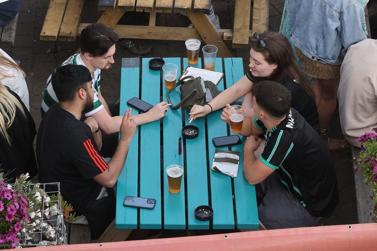 People drinking and smoking in a pub garden  in Brighton