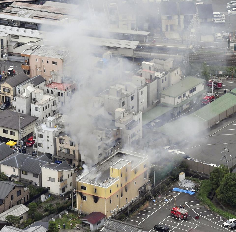 Smoke billows from a Kyoto Animation building, bottom, in Kyoto, western Japan, Thursday, July 18, 2019. The fire broke out in the three-story building in Japan's ancient capital of Kyoto, after a suspect sprayed an unidentified liquid to accelerate the blaze, Kyoto prefectural police and fire department officials said.(Kyodo News via AP)