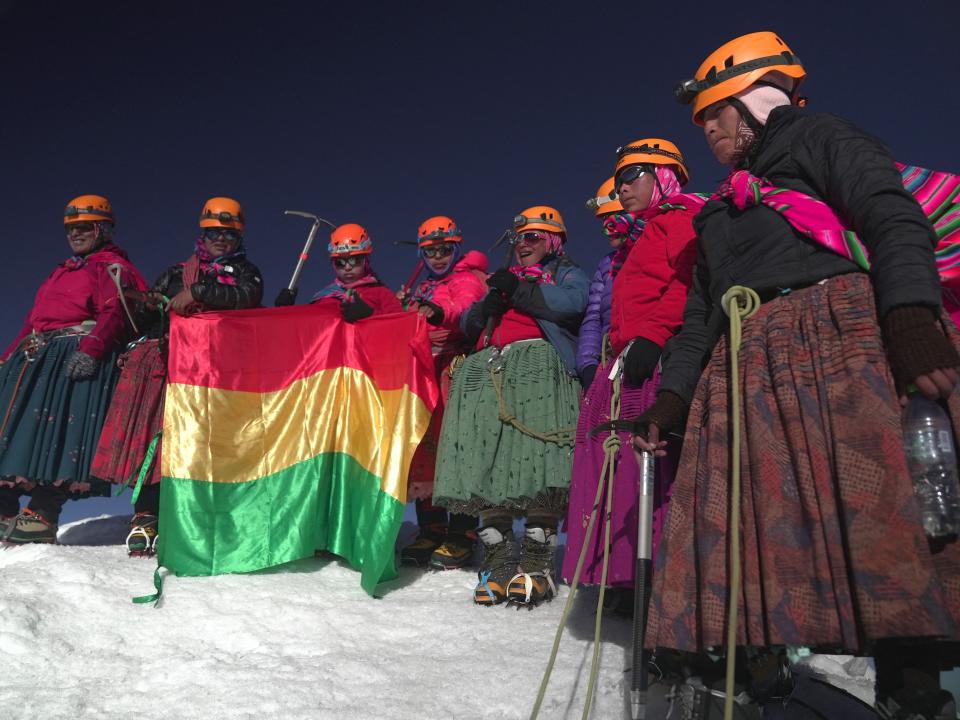The Cholita climbers unfurl their flag at the summit of Huayna Potosi mountain.