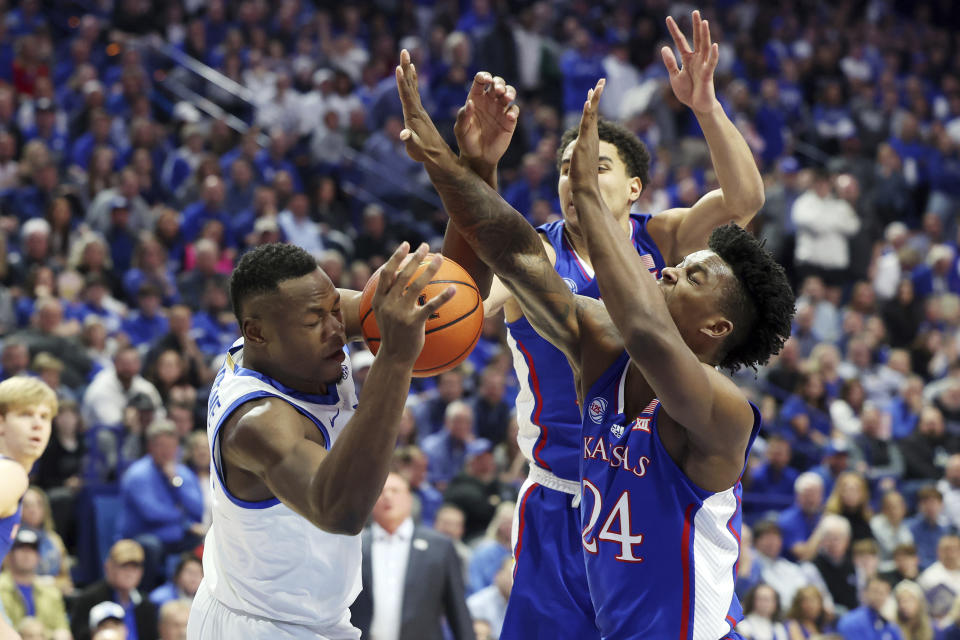 Kentucky's Oscar Tshiebwe, left, is defended by Kansas' K.J. Adams Jr. (24) and Kevin McCullar Jr., middle, during the first half of an NCAA college basketball game in Lexington, Ky., Saturday, Jan. 28, 2023. (AP Photo/James Crisp)