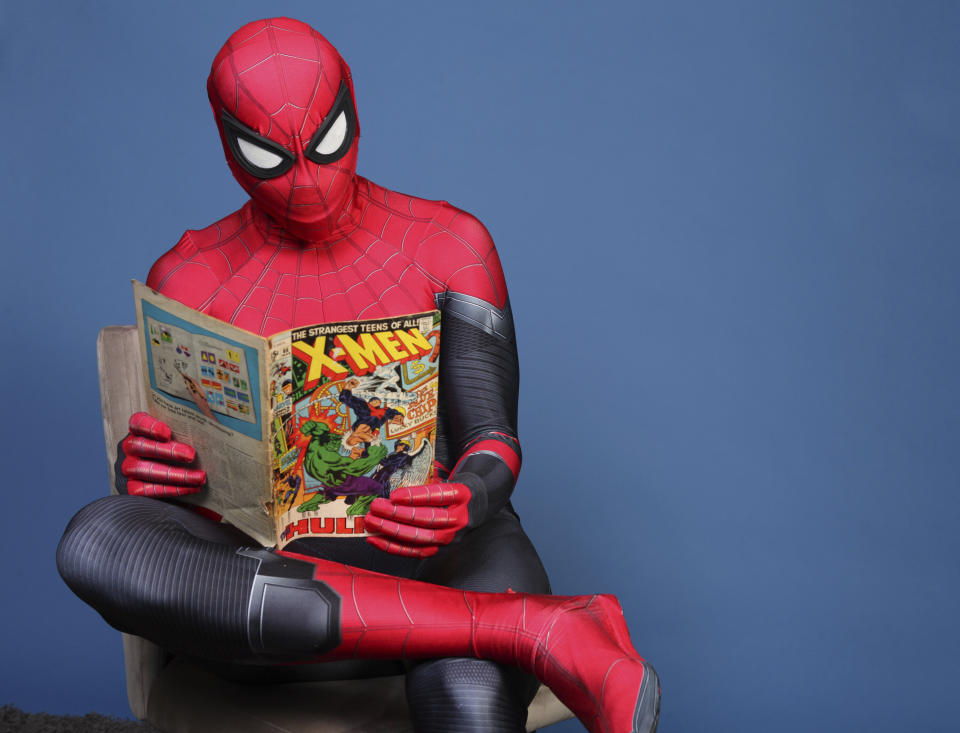 Evan Nuzum reads a comic book dressed as Spider-Man.