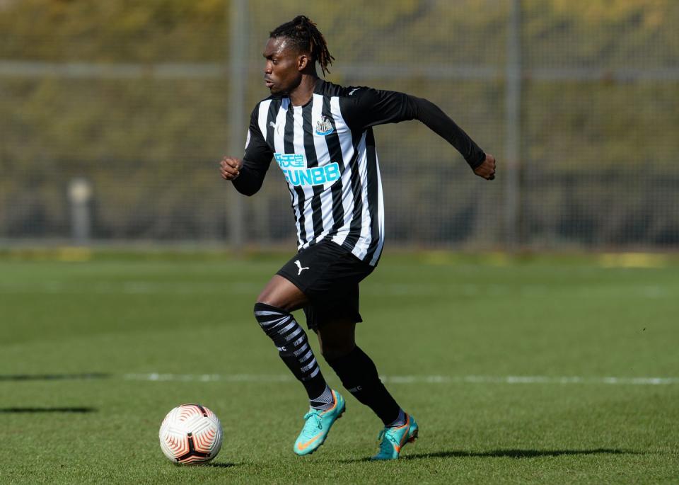 a man in a black and white striped soccer uniform kicking a soccer ball on a field and running