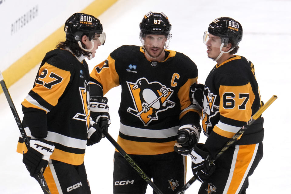 Pittsburgh Penguins' Sidney Crosby (87) celebrates with Ryan Graves (27) and Rickard Rakell after his empty-net goal during the third period of an NHL hockey game against the Seattle Kraken in Pittsburgh, Monday, Jan. 15, 2024. It was Crosby's second goal of the game. (AP Photo/Gene J. Puskar)