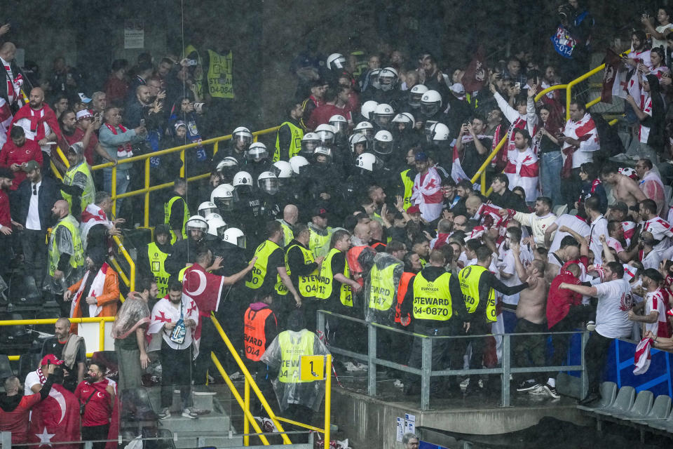 Riot police separate Turkish and Georgian fans after they briefly scuffled ahead of a Group F match between Turkey and Georgia at the Euro 2024 soccer tournament in Dortmund, Germany, Tuesday, June 18, 2024. (AP Photo/Andreea Alexandru)