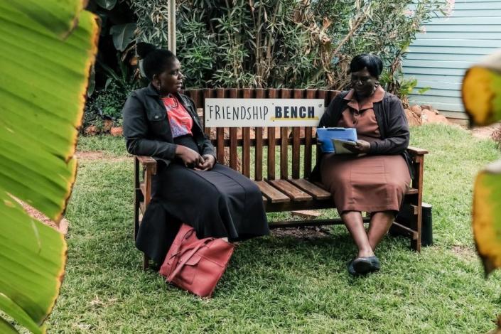 Counsellor &quot;Gogo&quot; Shery Ziwakayi (R) sits on a bench in conversation with a client &quot;Muzukuru&quot; Choice Jiya (L) during a private counselling session at the Friendship Bench in Harare on November 4, 2022. - A Zimbabwean doctor has come up with a novel way of providing desperately needed, yet free mental health therapy for Zimbabweans using elderly lay health workers referred to as grandmothers. Dubbed the Friendship Bench, psychiatry professor Dixon Chibanda's creation is a wooden park bench where people experiencing common mental disorders such as anxiety and depression sit and receive therapy from grandmothers. Now the model is temporarily being exported to FIFA World Cup in Qatar later this month to cast the spotlight on mental health. The Friendship Bench in partnership with the World Health Organisation (WHO) will set up 32 friendship benches at various spots in Qatar, each representing the competing teams.