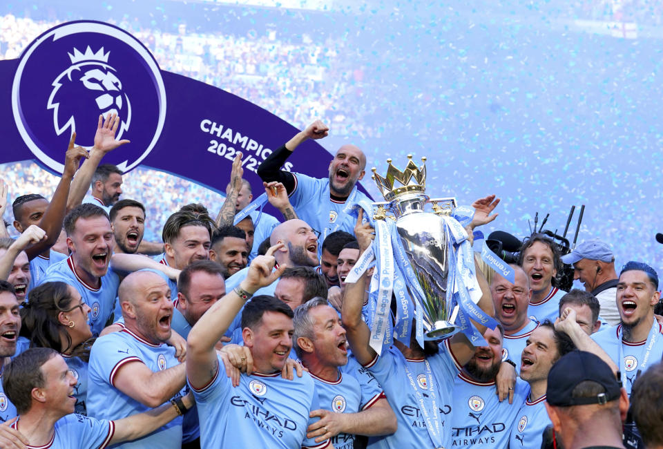 Manchester City players and staff including Pep Guardiola celebrate with the Premier League trophy after their English Premier League title win at the end of the English Premier League soccer match between Manchester City and Chelsea at the Etihad Stadium in Manchester, England, Sunday, May 21, 2023. (Martin Rickett/PA via AP)