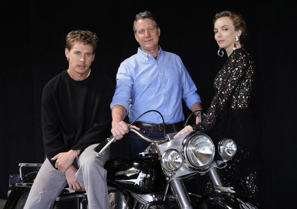 Jeff Nichols, center, writer/director of "The Bikeriders," poses with cast members Austin Butler, left, and Jodie Comer, Thursday, May 30, 2024, in Los Angeles. The motorcycle is a 1965 Harley Davidson Pan Head that Butler rode in the film. (AP Photo/Chris Pizzello)