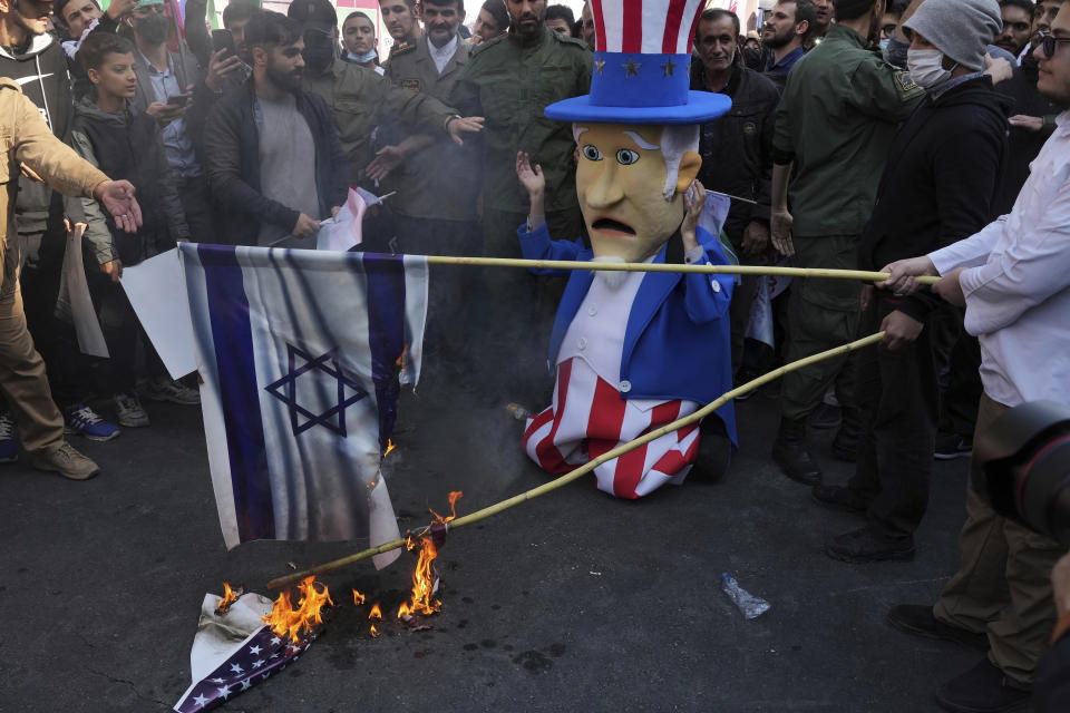 Iranians burn representations of the U.S. and Israeli flags as a man wearing Uncle Sam costume cries during annual demonstration in front of the former U.S. Embassy in Tehran, Iran, Friday, Nov. 4, 2022. Iran on Friday marked the 1979 takeover of the U.S. Embassy in Tehran as its theocracy faces nationwide protests after the death of a 22-year-old woman earlier arrested by the country's morality police. (AP Photo/Vahid Salemi)